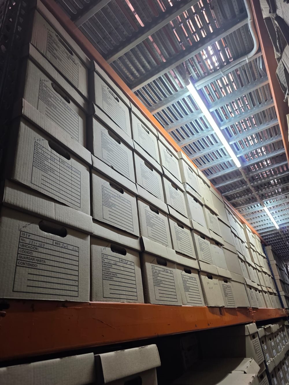 Cajas de archivo rotuladas y apiladas en una estantería del depósito de SOS Archivos